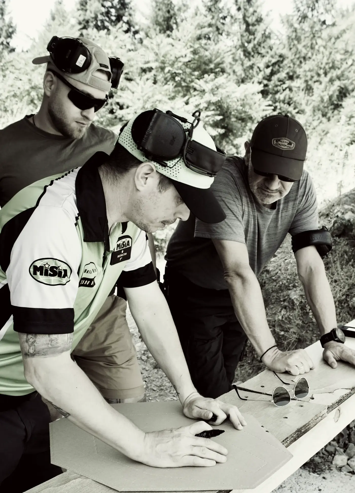 An instructor marking the hits on a target for two students